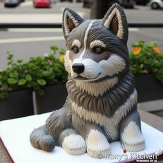 a statue of a dog sitting on top of a white table next to some plants