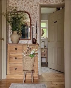 a room that has a dresser and mirror on the wall, with flowers in a basket next to it