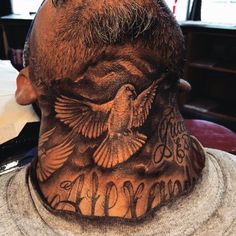 the back of a man's head with tattoos on his face and neck,