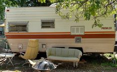 an old camper is parked next to some chairs