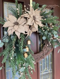 a wreath with poinsettis and pine cones hanging from it's front door