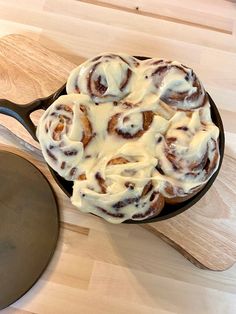 a pan filled with cinnamon rolls sitting on top of a wooden table next to a spatula