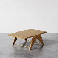 a small wooden table sitting on top of a cement floor next to a white wall