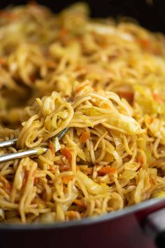 a bowl filled with noodles and carrots on top of a stove