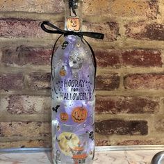 a bottle with halloween decorations on it sitting next to a brick wall