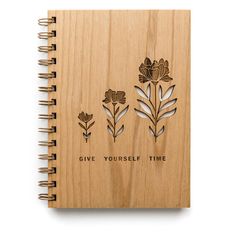 a wooden notebook with three flowers and the words give yourself time