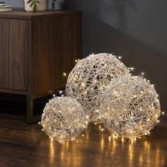 three lighted balls sitting on top of a wooden floor