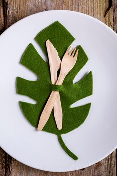 two wooden forks and spoons are placed on top of a green leaf shaped plate