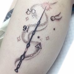 a harry potter wand tattoo on the thigh, with stars and sparkles around it