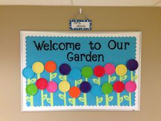 a welcome to our garden sign hangs on the wall in an office building with colorful paper flowers