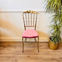 a pink chair sitting next to a potted plant