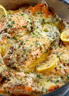 a pan filled with fish covered in cheese and lemons