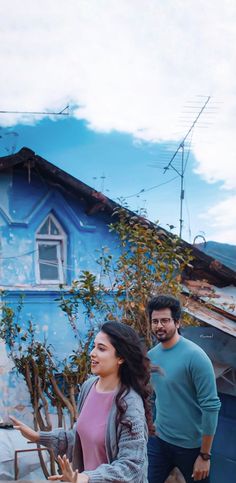 two people standing in front of a blue house