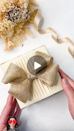 someone is holding a small gift box with a bow on it and ribbon around it