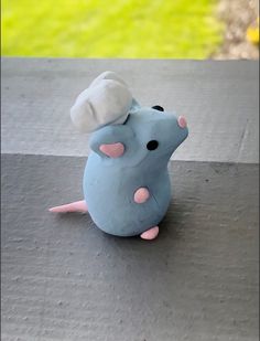 a small blue toy mouse sitting on top of a cement slab with grass in the background