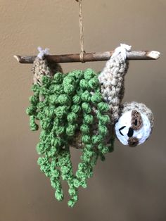 a crocheted slotty hanging from a branch with a stuffed animal on it