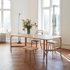 a dining room table and chairs in front of large windows