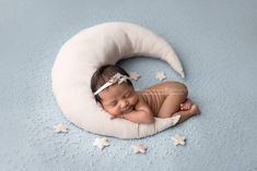 a baby is sleeping in a white crescent on a blue blanket with stars around it