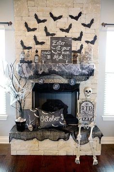 a fireplace decorated for halloween with black and white decorations on top, bats hanging from the mantel