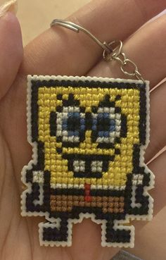 a hand holding a pixel keychain with an image of a minion on it