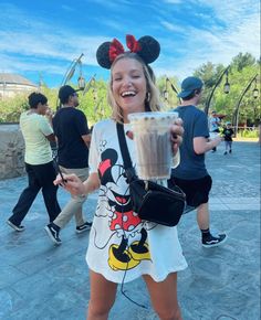 a woman is holding a drink and smiling at the camera