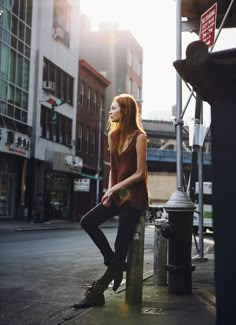 a woman is sitting on a post in the city