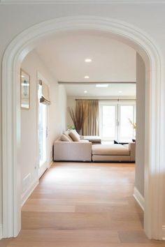 an archway leading into a living room with white walls and wood floors on either side