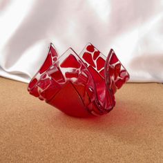 three red glass vases sitting on top of a brown table next to a white curtain