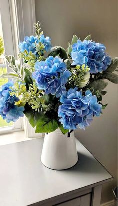 a white vase filled with blue flowers on top of a table