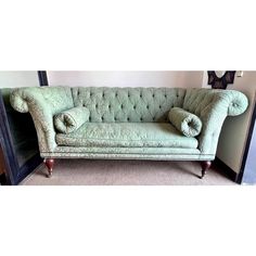 a green couch sitting on top of a carpeted floor