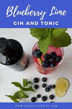 blueberry lime gin and tonic in a glass with mint leaves, lemon wedges, and ice