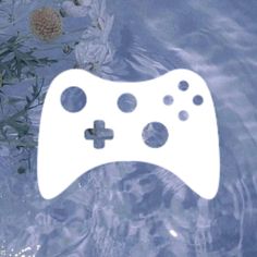 a video game controller floating in water next to flowers and leaves on the surface,