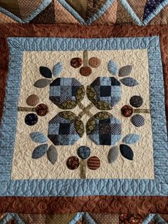 a quilted wall hanging with blue and brown designs