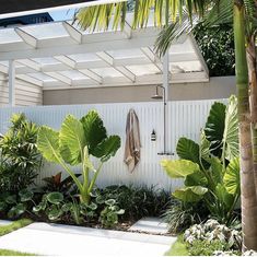 an outdoor shower surrounded by tropical plants and palm trees on the side of a house