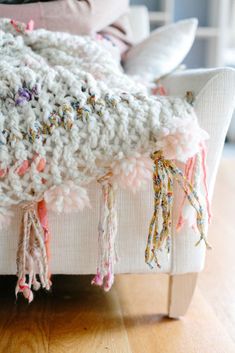 a white crocheted blanket sitting on top of a couch next to a pillow