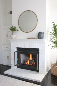 a white fireplace with a mirror above it