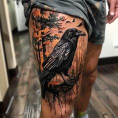 a man's leg with a black crow on it and trees in the background