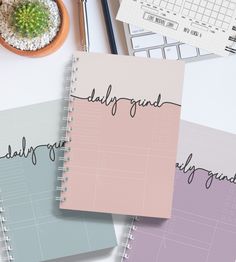 three notebooks sitting on top of a desk next to a plant and pen with the words daily journal written in cursive writing