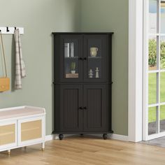 a black cabinet sitting on top of a hard wood floor next to a white bench