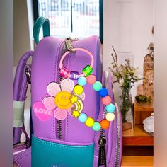 a purple backpack with a flower and beads on it