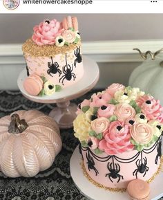 two cakes decorated with pink and yellow flowers on top of white plates next to pumpkins