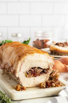 a meatloaf roll on a cutting board with other food items in the background