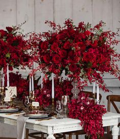 the table is set with red flowers and candles