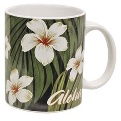 a coffee mug with white flowers and palm leaves on the inside is shown in front of a white background