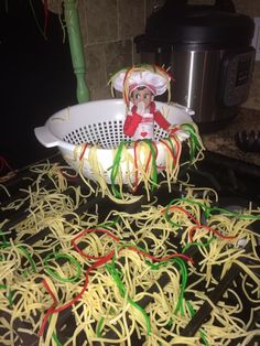 an elf is sitting in a colander filled with noodles