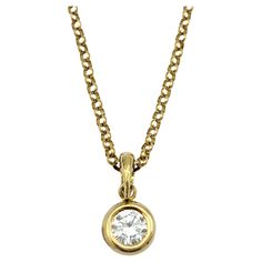 Crafted with timeless elegance, this solitaire diamond pendant necklace exudes sophistication and refinement. The pendant features a single round diamond, securely nestled within a sleek bezel setting made of lustrous 18 karat yellow gold. The bezel setting not only highlights the brilliance of the diamond but also provides a modern and minimalist aesthetic. Suspended from a delicate chain also fashioned from 18 karat yellow gold, this necklace adds a touch of luxury to any ensemble. The simplicity of the design allows the beauty of the diamond to take center stage, making it a versatile and classic piece suitable for everyday wear or special occasions. Whether worn alone for understated elegance or layered with other necklaces for a personalized look, this bezel set round diamond solitair Luxury Solitaire Necklace With Bezel Setting, Luxury Gold Solitaire Necklace For Everyday, Solitaire Diamond Pendant, Round Solitaire, Solitaire Pendant Necklace, Solitaire Diamond, Delicate Chain, Solitaire Pendant, Understated Elegance