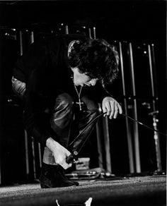 black and white photograph of a man bending over with his hand on the ground while holding a pair of scissors