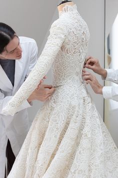 a woman in a white dress is being fitted to a mannequin