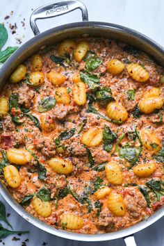 pasta with spinach and sauce in a pan on top of a white tablecloth