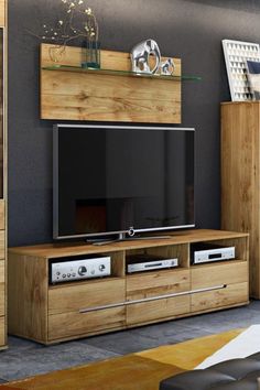 a living room with a large television on top of a wooden entertainment center in front of a window